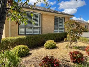 a house with bushes and flowers in front of it at Yass Valley Stays - Convenient & Comfortable in Yass
