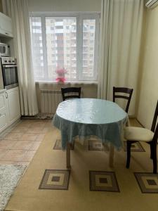 una cucina con tavolo, sedie e finestra di Квартира a Astana