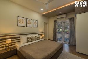 een slaapkamer met een groot bed en een raam bij StayVista's Silver Grove - Serene Haven with Expansive Lawn & Terrace in Nashik