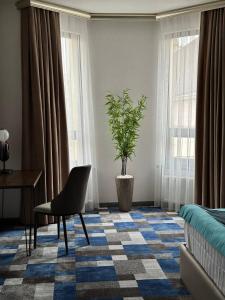 um quarto com uma cadeira, uma mesa e uma planta em HL 212 em Tashkent