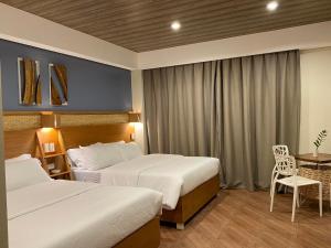 a hotel room with two beds and a table at Acacia Garden Inn in Coron