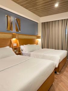2 Betten in einem Hotelzimmer mit weißer Bettwäsche in der Unterkunft Acacia Garden Inn in Coron