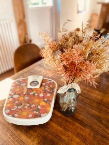 una mesa con un móvil y un jarrón con flores en La folie douce, maison d'hôtes, 