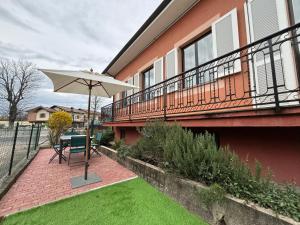 a patio with a table and an umbrella at Villanova d'Asti Charming House with barbecue by Alterego in Villanova dʼAsti