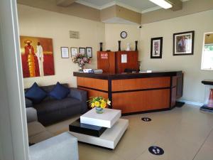 a waiting room with a reception desk and a couch at Queen's Place in Johannesburg