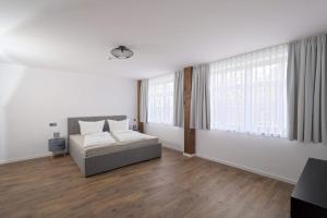 a white bedroom with a bed and a large window at Ferienqartier- Forsthaus in Bad Gottleuba