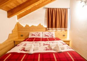 a bedroom with a red and white bed with two towels at Baita Stabli-Rifugio Luxury a 1700 mt in Mezzana