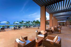 a resort patio with chairs and tables and the ocean at Amaya Beach Passikudah in Pasikuda