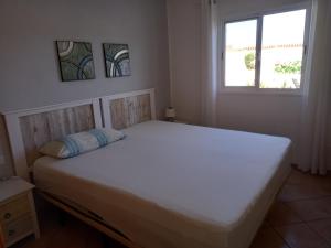 - un lit blanc dans une chambre avec fenêtre dans l'établissement casa yamila, à Costa Calma