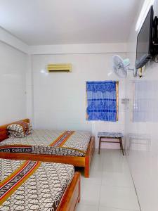 Habitación con 2 camas, TV y mesa. en Nhà Trọ Số 2 en áº¤p VÄ©nh ÃÃ´ng