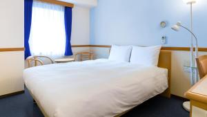 a bedroom with a large white bed and a window at Toyoko Inn Kagoshima chuo eki Higashi guchi in Kagoshima