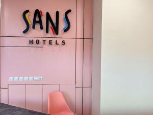 a pink room with a chair and a hotel sign at SANS Hotel Premiere Majapahit Semarang in Semarang