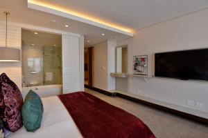 una camera da letto con un grande letto e un grande televisore di Houghton Suites a Johannesburg