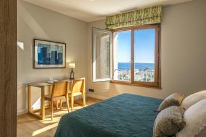 Villa Cintolino في Brando: غرفة نوم بسرير وطاولة مطلة على المحيط