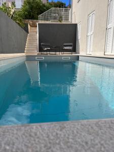 a swimming pool with two chairs next to a building at Apartment Arte Vrbnik in Vrbnik