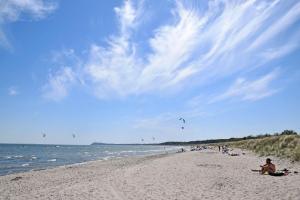 um grupo de pessoas em uma praia soltando pipas em Ferienwohnungen im Haus am Deich em Middelhagen