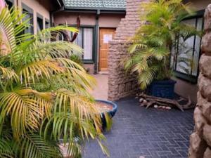 a courtyard with palm trees in front of a house at Dula Monate Holiday Flats in Bela-Bela