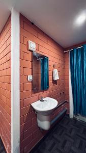 baño con lavabo y pared de ladrillo en The Stream View Villas Wayanad en Vythiri