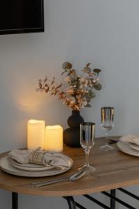 a wooden table with plates and wine glasses on it at Apartamenty przy Promenadzie by Renters in Świnoujście