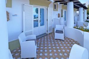 una veranda con sedie bianche e una porta di Dependance La Caletta a Panarea