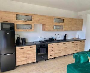 a kitchen with wooden cabinets and a black refrigerator at Apartament Guziczek2 in Nowy Targ