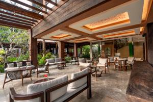 an outdoor patio with tables and chairs and windows at AnandaDara Ubud in Ubud