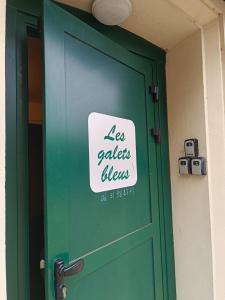 Una puerta verde con un cartel. en Les Galets Bleus, en Étretat