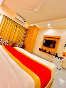 Habitación de hotel con cama de rayas rojas y amarillas en Amahi Inn - Sector 48 en Gurgaon