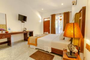 una camera con letto, scrivania e lampada di Elysia Sigiriya Hotel a Dambulla
