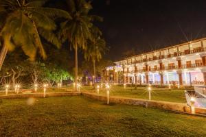 un edificio con palme e luci di fronte ad esso di Elysia Sigiriya Hotel a Dambulla