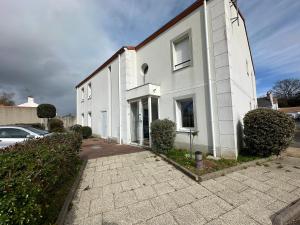 ein weißes Gebäude mit einem davor geparkten Auto in der Unterkunft La garenne, près des commerces in Saint-Jean-de-Monts