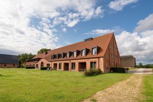 a brick building with a grass field in front of it at Kultur Gut Hasselburg in Altenkrempe +34 photos