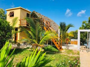 une maison jaune avec des palmiers devant elle dans l'établissement Adventurevilla, à Kendwa