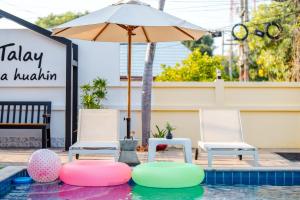 - une piscine avec 2 chaises et un parasol dans l'établissement ไอทะเล พูลล่า หัวหิน I-Talay Poolvilla huahin, à Hua Hin