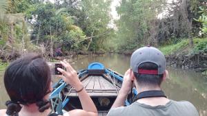 twee mensen die foto's maken van een boot op een rivier bij Dorm Can Tho in Can Tho