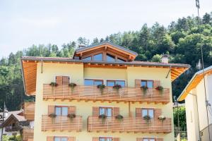 un edificio amarillo con un balcón con flores. en B&B al Borgo en San Lorenzo in Banale