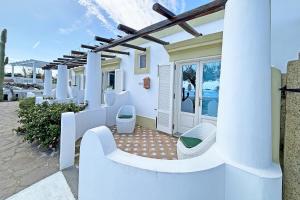 Cette maison blanche dispose d'une terrasse avec des chaises. dans l'établissement Dependance La Caletta, à Panarea