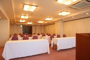 川崎市にあるホテル梶ヶ谷プラザの白いテーブルと椅子、照明付きの会議室