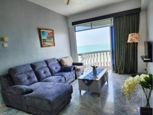 Glory Beach Resort 7+2 PAX Seaview Suite في بورت ديكسون: غرفة معيشة مع أريكة وطاولة