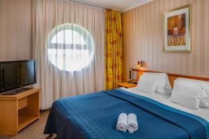 a hotel room with a bed with two white slippers on it at Hotel Vital in Zalakaros