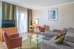 a living room with a couch and a tv at Hotel Vital in Zalakaros