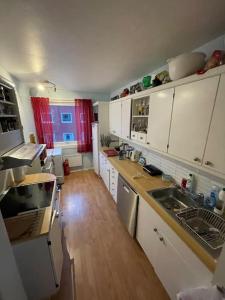 cocina con armarios blancos y suelo de madera en Narvik sentrum en Narvik