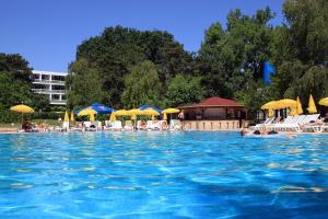 a swimming pool with chairs and umbrellas and people in it at Hotel 2D Resort and Spa in Neptun