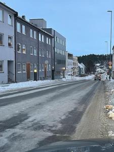 una calle vacía con edificios y un coche en ella en Narvik sentrum en Narvik