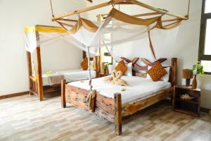 a bedroom with two beds and a canopy bed at Z-Lodge Zanzibar in Kiwengwa