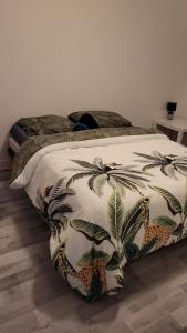 a bed with a comforter with palm trees on it at villa skys France in Gien