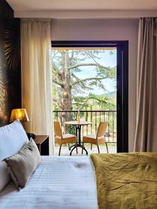 a bedroom with a bed and a balcony with a table at Hotel Bastide & SPA - Villa de Lourmarin in Lourmarin