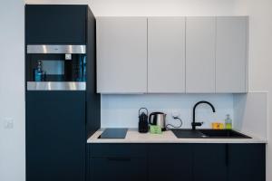 a kitchen with black and white cabinets and a sink at All in Lyon | T2 design & climatisé – Centre in Lyon