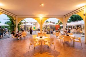 a restaurant with yellow chairs and tables and people sitting at tables at Italia Family Camping Village Viareggio in Torre del Lago Puccini