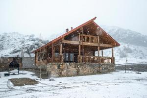 una cabaña de madera en la nieve con nieve cayendo en Ranger Campus Eco Lodge en Urtsʼadzor